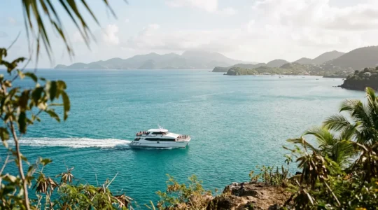 Vue panoramique d'un ferry traversant les eaux turquoise entre deux îles de la Guadeloupe sous un ciel ensoleillé