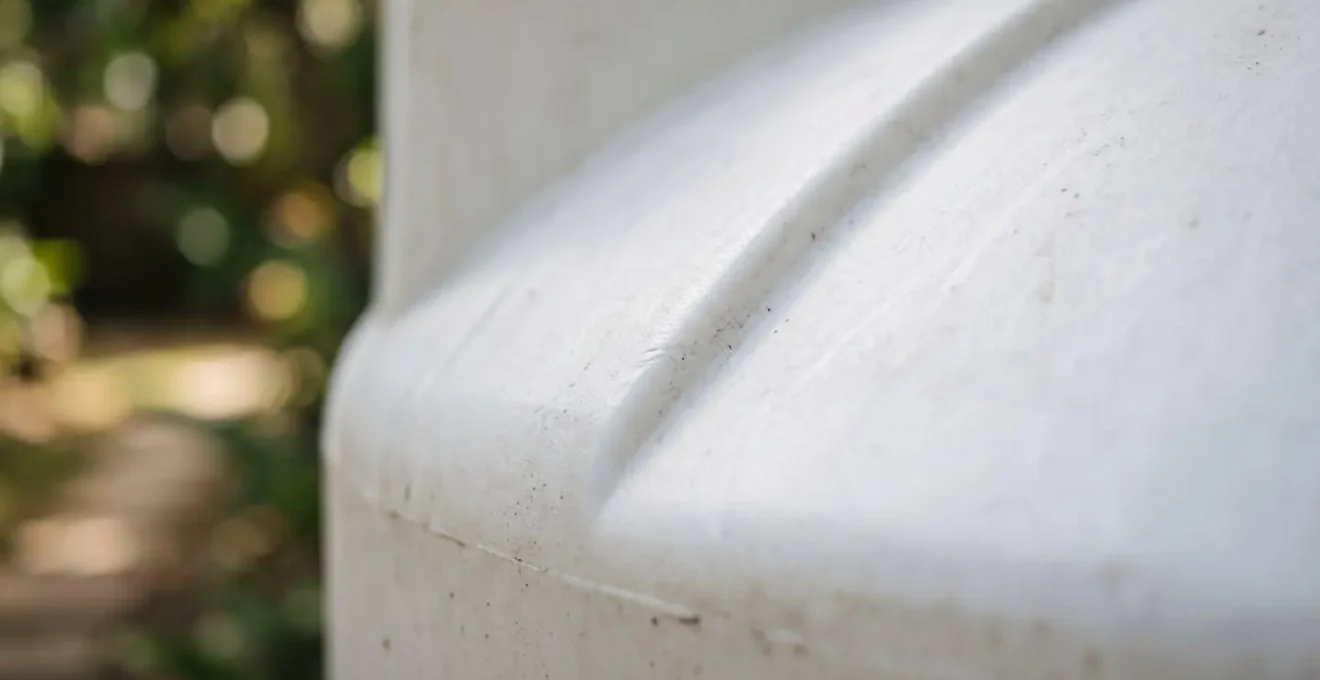 Grande citerne d'eau blanche installée dans un jardin tropical luxuriant en Guadeloupe, symbolisant l'autonomie face aux coupures d'eau
