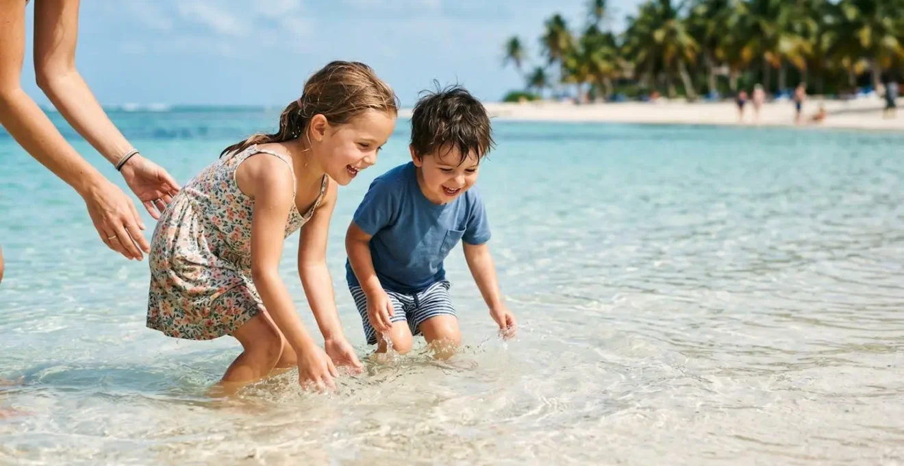 Jeunes enfants jouant dans un lagon turquoise peu profond avec fond sableux en toute sécurité, Grande-Terre