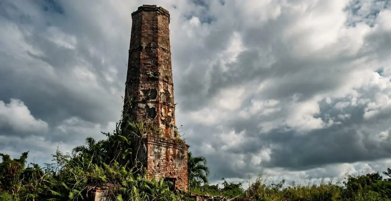 Cheminée industrielle en brique d'une ancienne sucrerie coloniale se détachant sur le ciel guadeloupéen